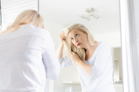 older blonde woman looking at herself in a mirror