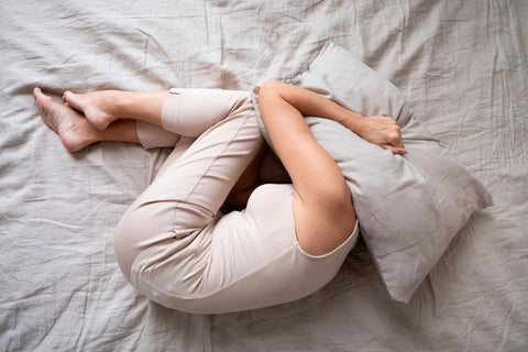 woman in bed with a pillow over her head