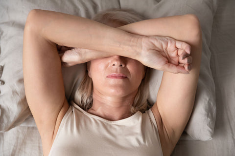 woman lying with her arms over her eyes