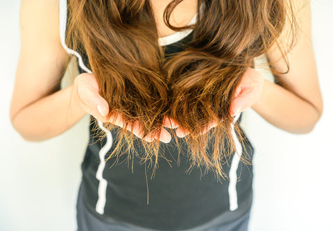 a woman with long brown hair cupping it in her hands