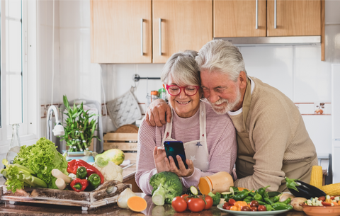 older couple hugging and smiling in the kitchen surrounded by vegetables