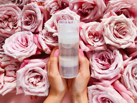 woman holding lubricant over a bunch of pink roses