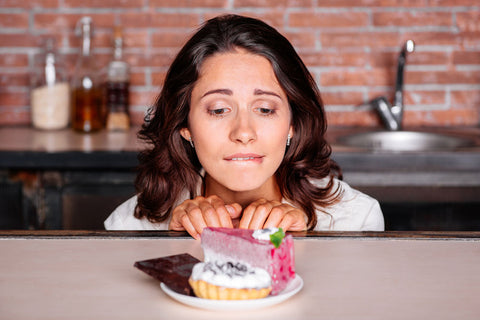 woman looking longingly at a piece of cake