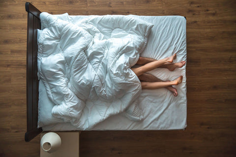 view from above of a couple in bed with only their feet showing 