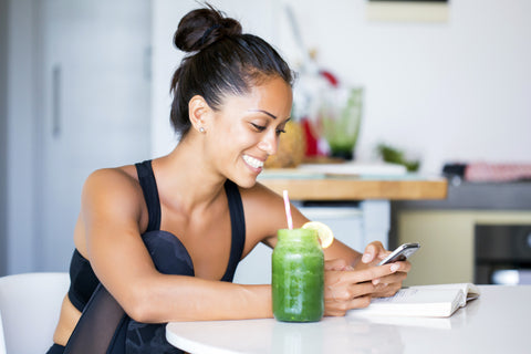 Woman drinking smoothie looking at her phone