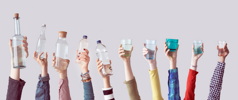 hands holding up water bottles and glasses of water