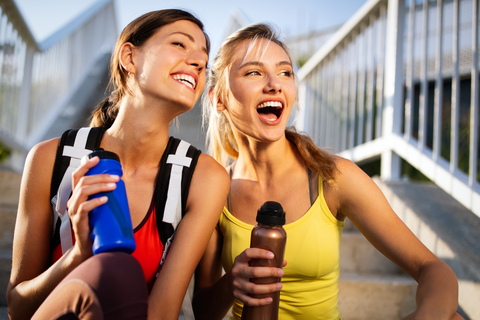 two athletic girls sitting with water bottles in their hands