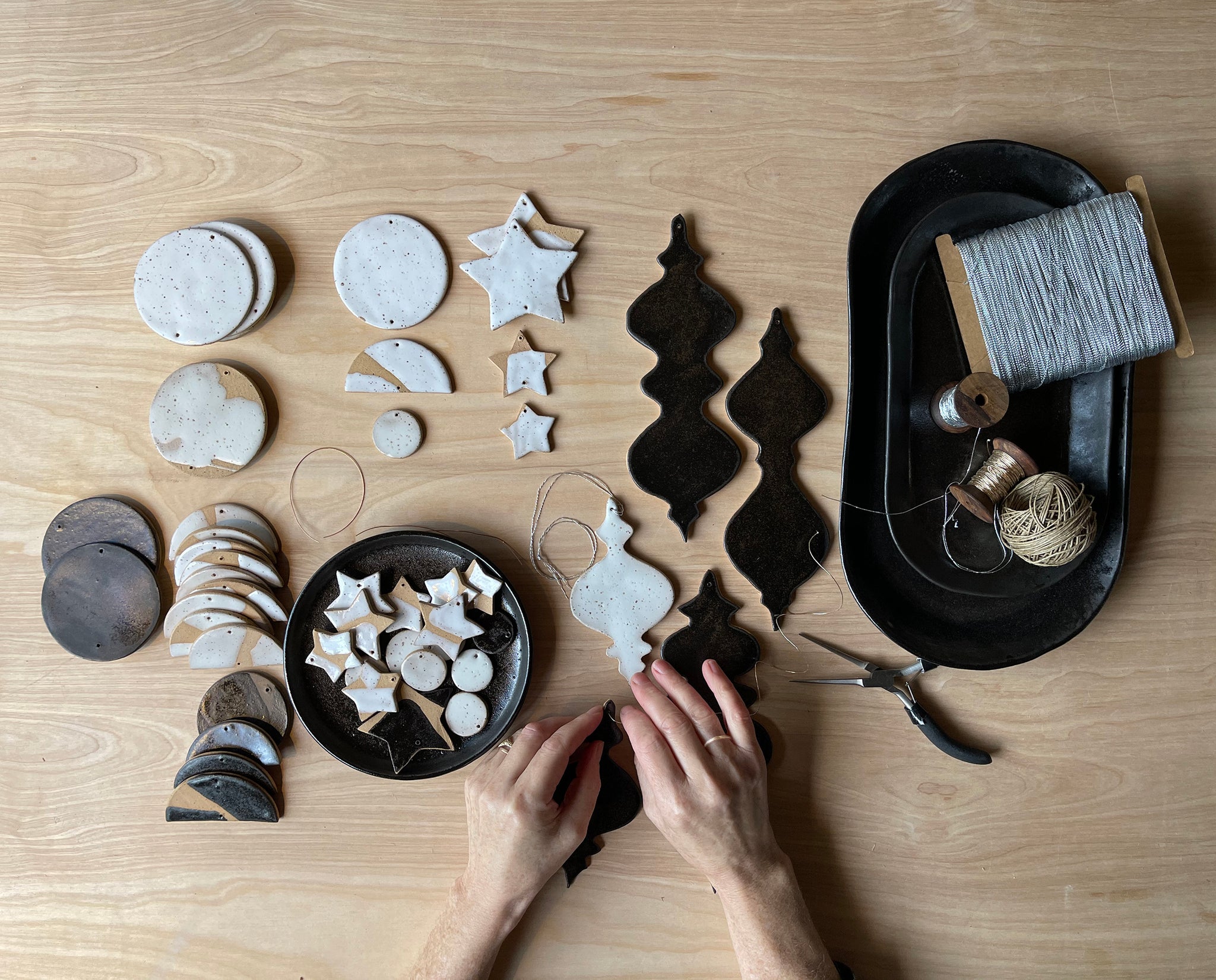 Top view image of Sarah Mitchell-Davison's hands threading one of her Arc Ceramics pieces. 