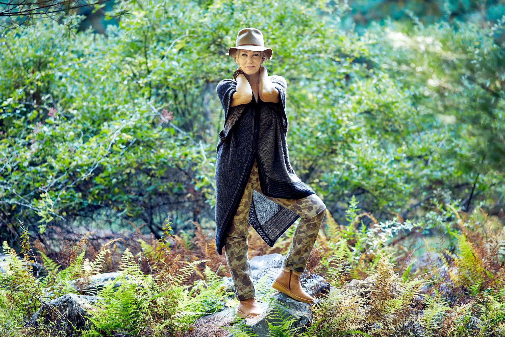 Full body image of Laura Chávez Silverman posing on a rock surrounded by nature.
