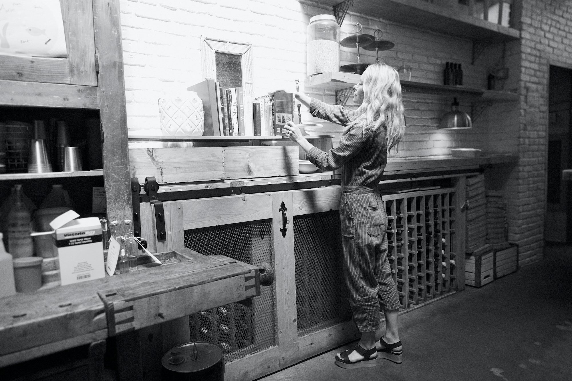 Black & white shot of Heather Tierney of picking out of a book from a shelf. 