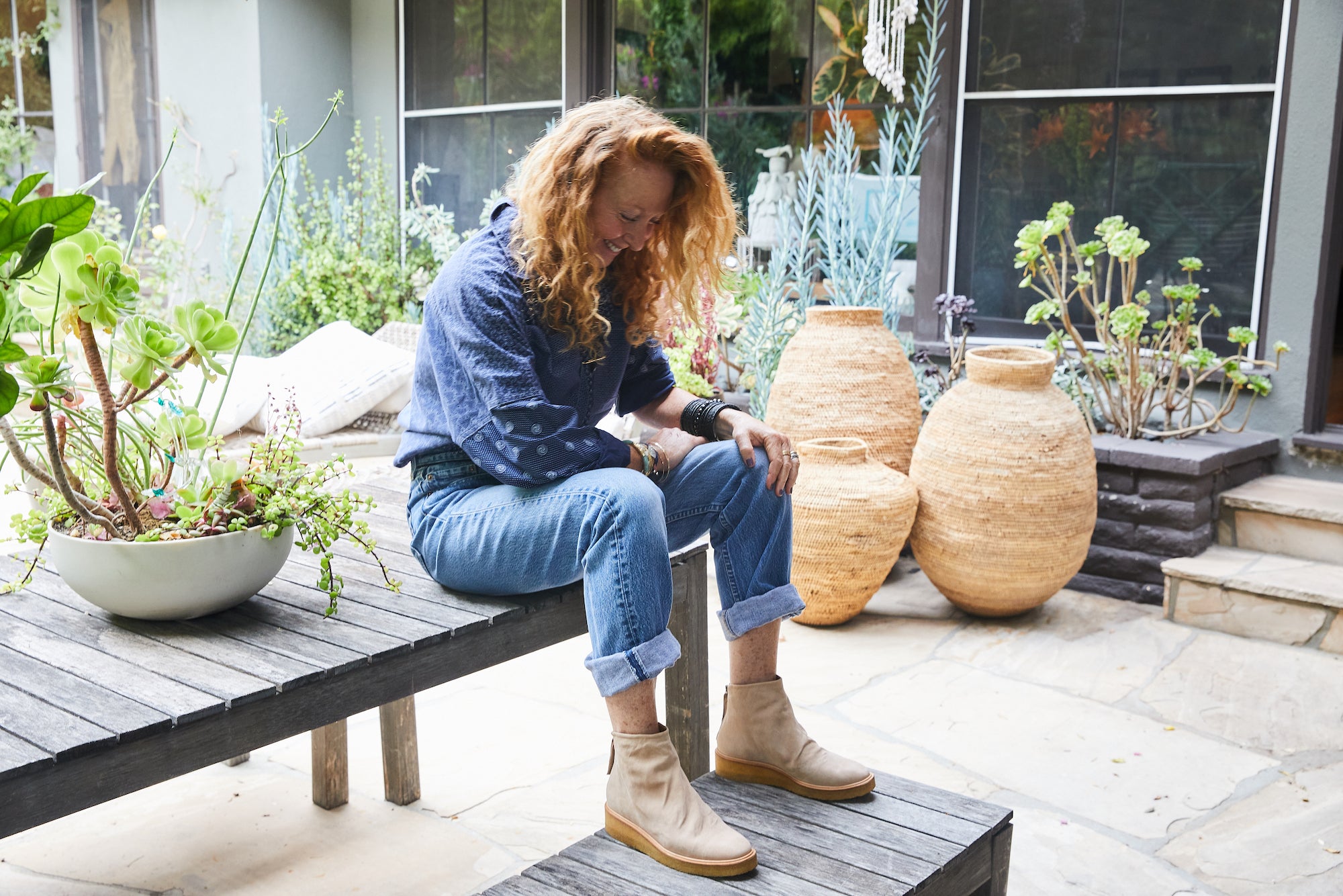 Tracy Marsh Hoffman sitting on an outdoor wooden table sporting the Hop Boot. 