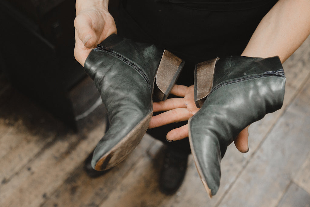 Image of Byron Valarezo's hands holding a pair of Coclico boots. 