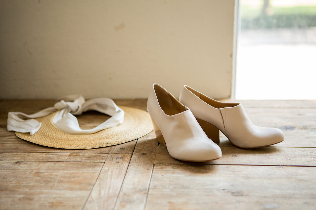 Sunlit picture of the Bonita Heel on a wooden table with a hat placed behind. 
