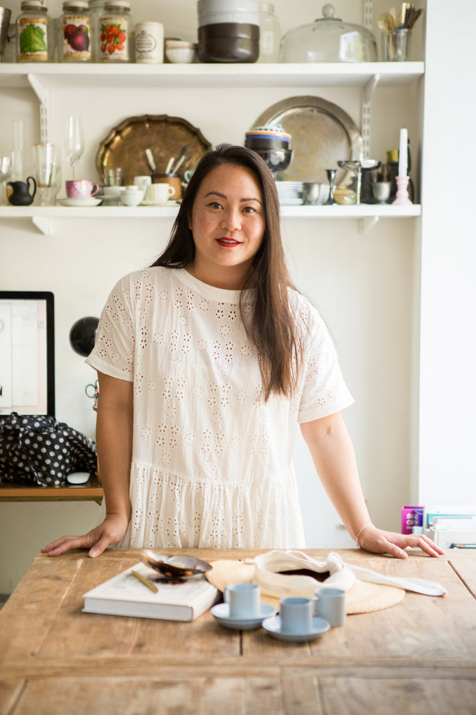 Diana Yen from of The Jewels of New York standing before a wooden table.  