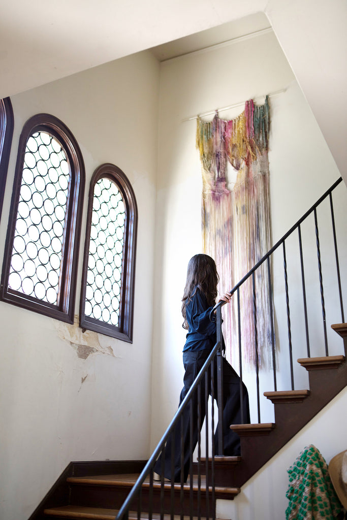 Erica Tanov going up the stairs looking at a piece of artwork hanging on the wall. 