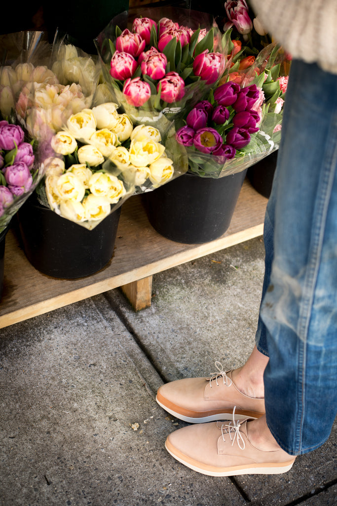 Image of Erin Boyle in the Coclico Pekos Wedge beside a flower shop. 