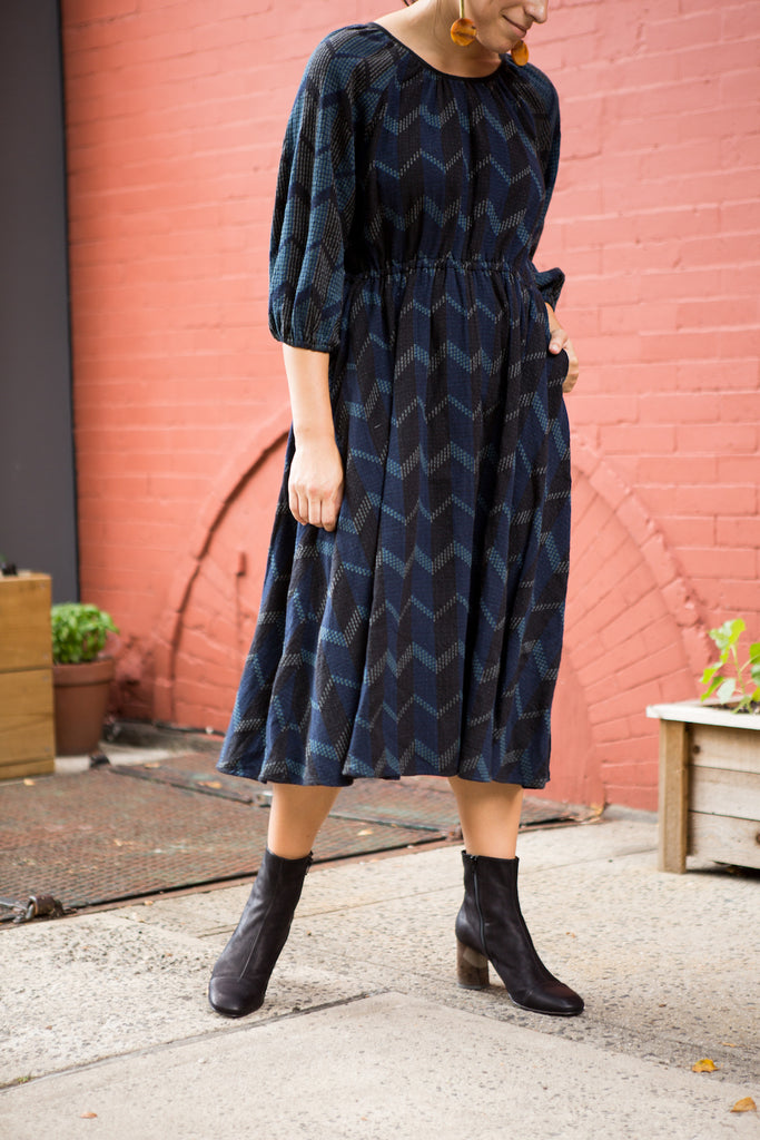 Model posing in the Coclico Laeve Bootie in Black leather paired with a patterned dress.