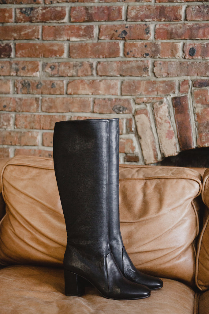 A side view picture of the Coclico Lulu Boot on a leather couch. 