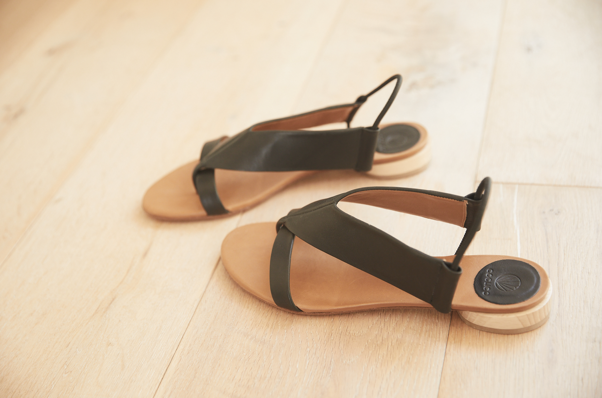 The Coclico Cardinal sandal on a wood floor.