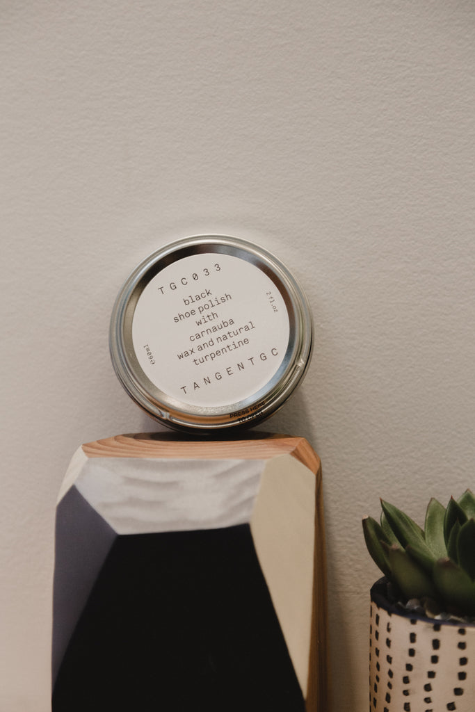 The Tangent GC black shoe polish placed on a wood block decor beside a plant. 
