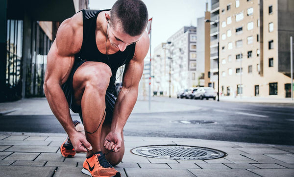 Fit Man Tying Shoe On Street