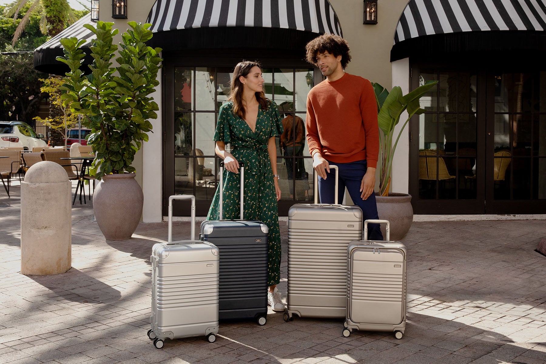 man and woman standing in front of hotel with 4 luggage pieces in front