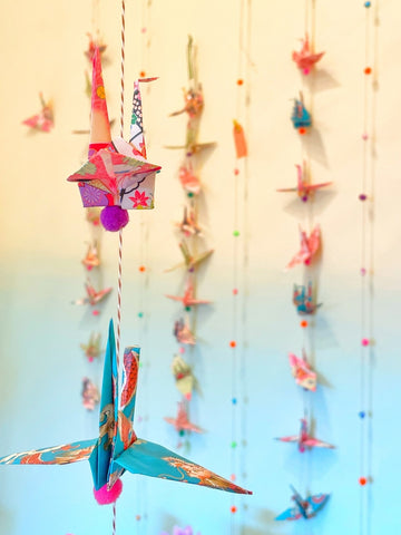 Paper Crane garlands hanging from ceiling with yellow to blue color gradient on wall