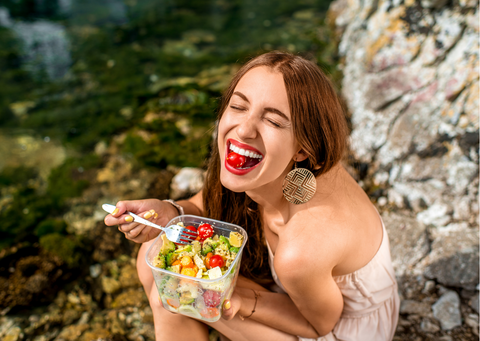A girl happily eating a salad