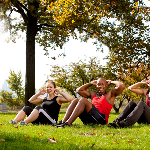 a group of people sitting on grass while doing some exercise