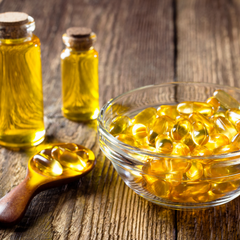 a bowl of fish oil softgels and small bottles of oil