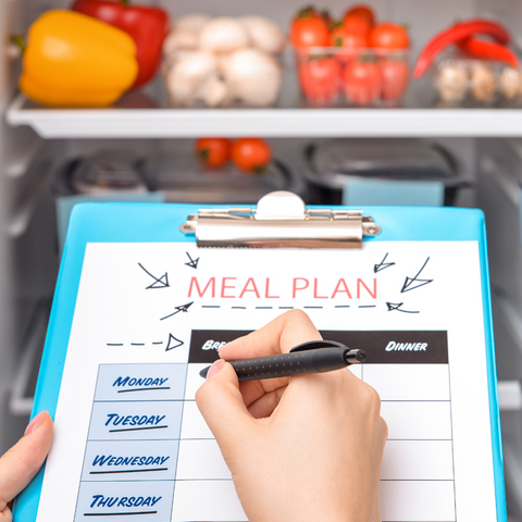 A hand holding meal plan paper and a pen