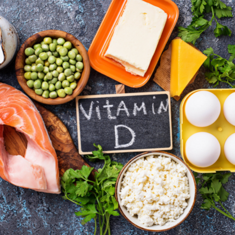 A blackboard with a written text Vitamin D surrounded by eggs, fish, and peas