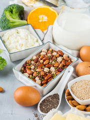 A flatlay image calcium food Milk, cheese, orange, broccoli, eggs and almonds
