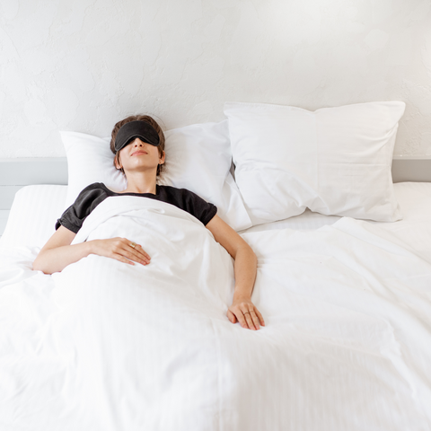 a person lying in bed with a eye mask