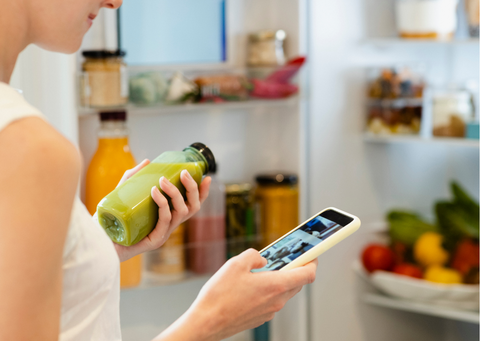 a person holding a bottle of juice and a phone