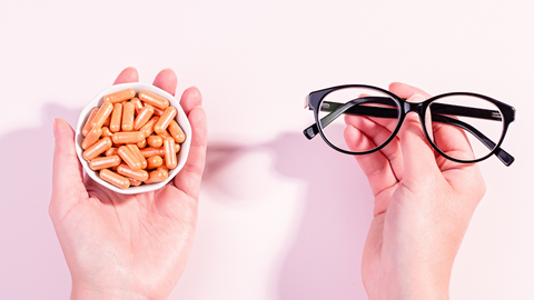 Hands holding supplements and eye glasses