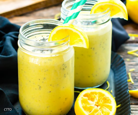 Two glass mason jars with yellow smoothie with yellow