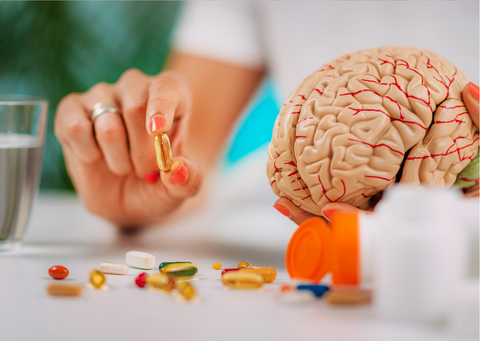 A hand holding a supplement with a sculpture of a brain