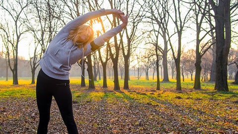 A girl stretching by the woods