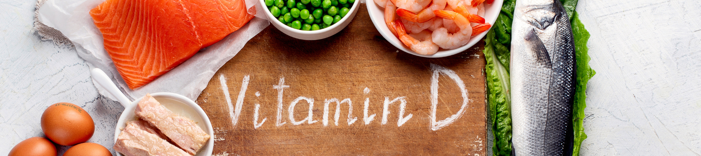 A flatlay image of a chopping board with a written text Vitamin D, surrounded by fish, shrimp, green peas and eggs