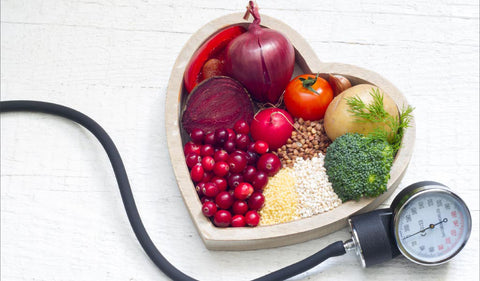 a heart shaped bowl with vegetables and a blood pressure meter