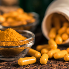 a close-up of a jar of turmeric capsules and a small bowl of turmeric powder