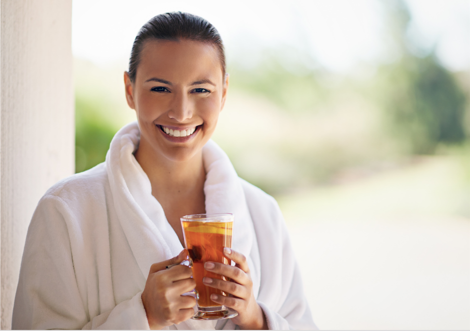 a person in a bathrobe holding a glass of tea