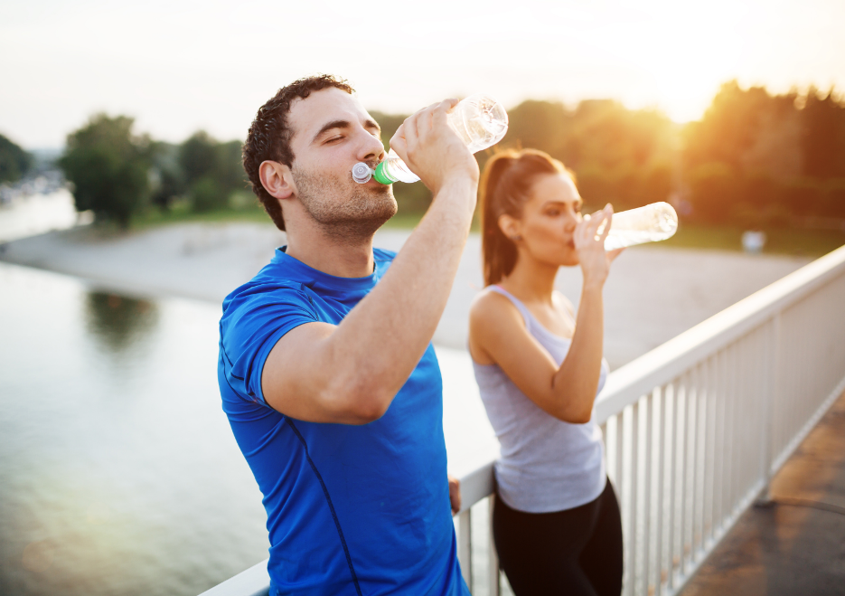 A man and a woman drinking water from a bottle