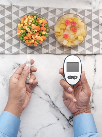 a person holding a blood glucose meter next to a bowl of food