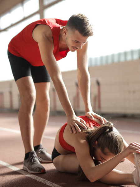 A man helping a woman do a stretch