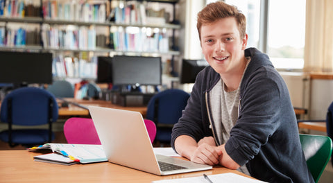 a boy sitting at a desk with a laptop