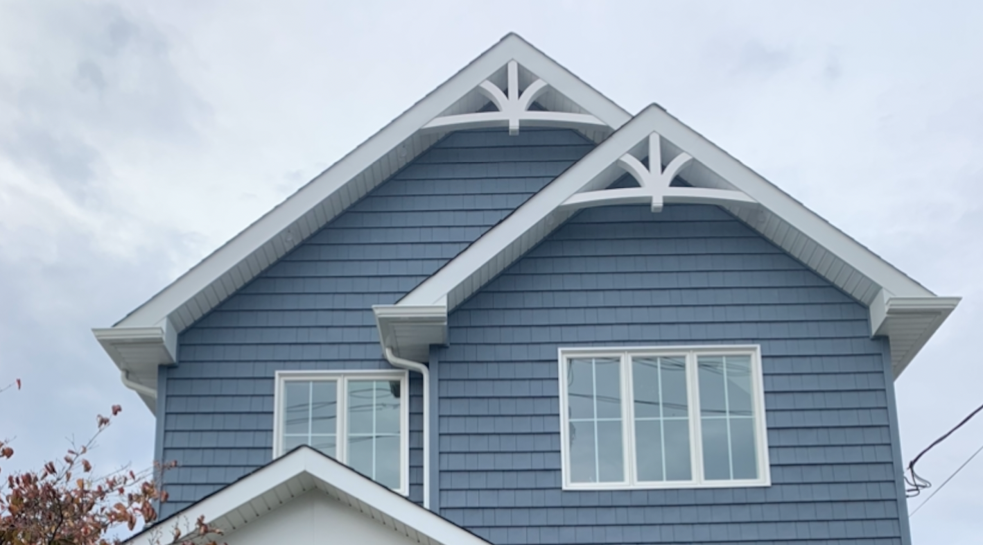 A blue home has a double gable roof with two white gable decorations.