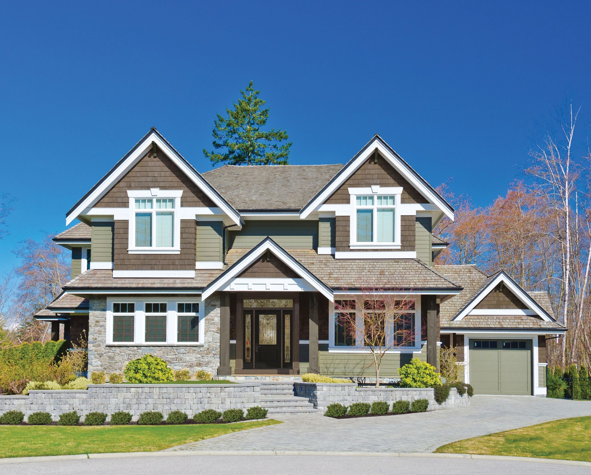 This two-story home has green, brown and stone siding with white trim.
