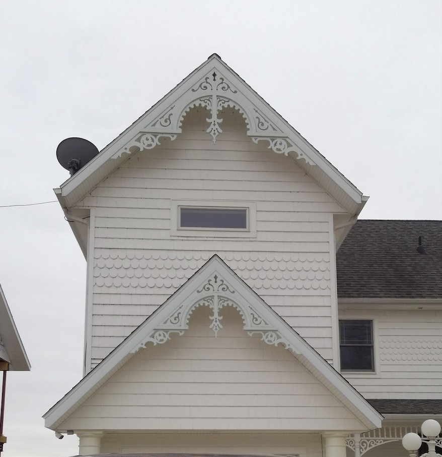 Close-up image of a white PVC gable bracket with Gingerbread-style scrollwork.